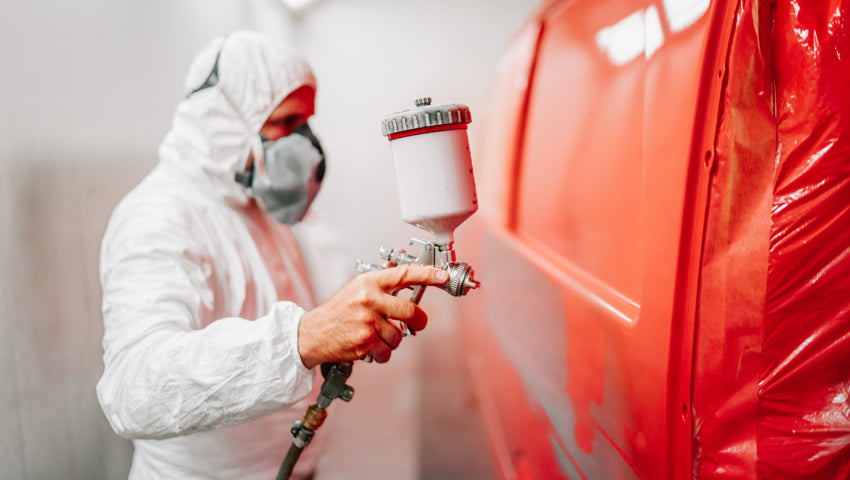 Hombre pintando un auto con pistola de aire.