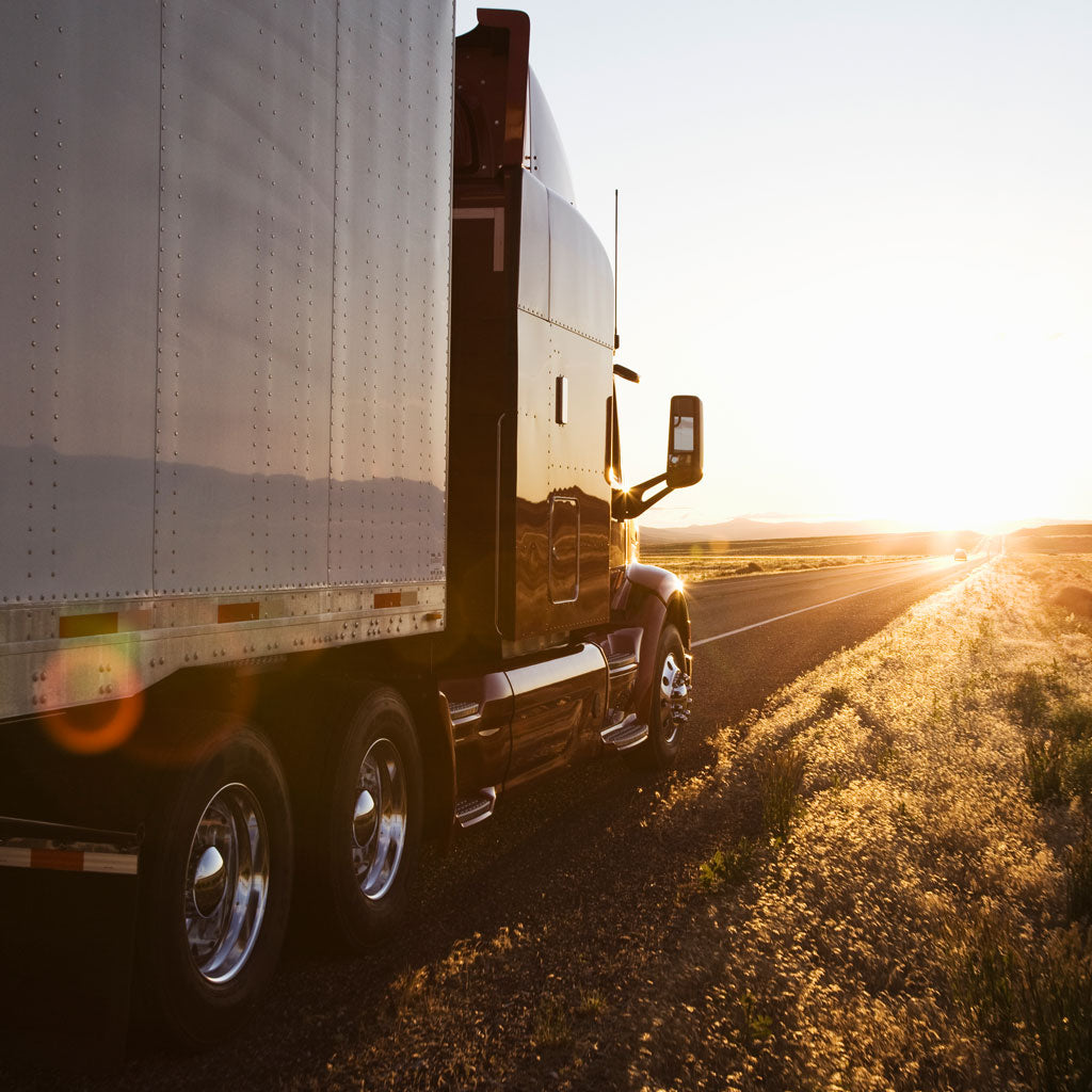 Concepto de logística con un trailer en la carretera frente al sol.